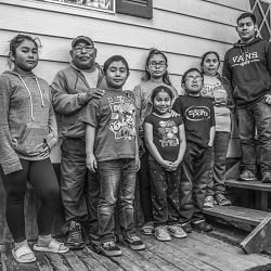 Family of farmworker standing in fron of a home
